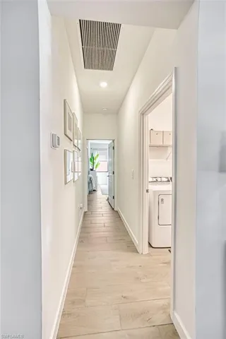Corridor featuring light wood finished floors, washer / dryer, and recessed lighting