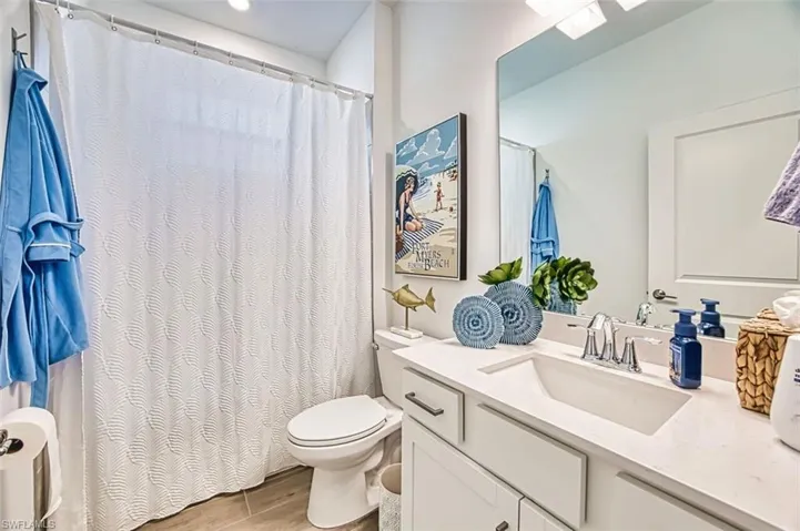 Bathroom with vanity, curtained shower, and light wood-style flooring