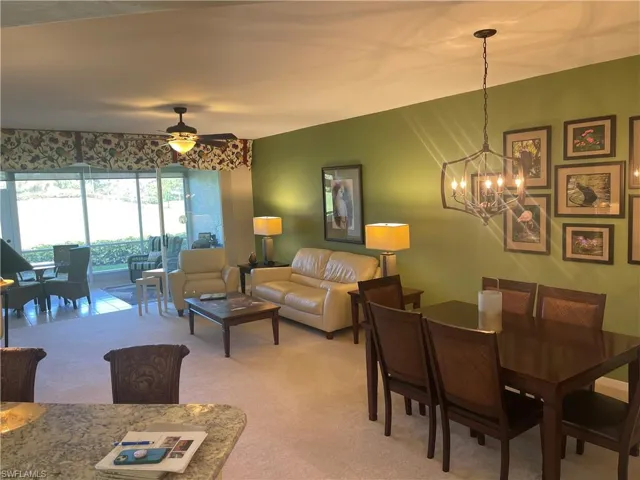 Dining space with light carpet and ceiling fan with notable chandelier