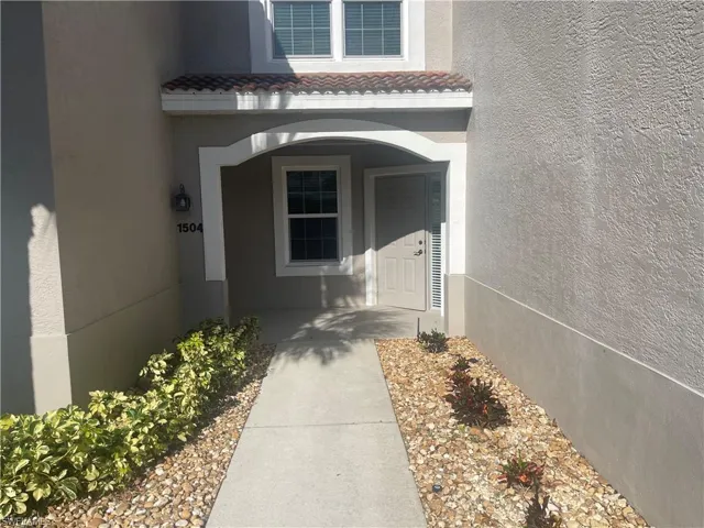 Property entrance featuring a tile roof and stucco siding
