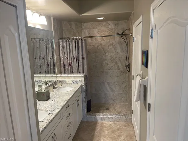 Full bath featuring a sink, a shower stall, and double vanity