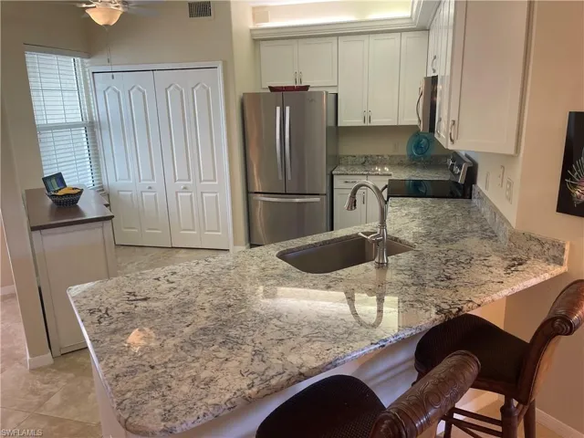 Kitchen featuring a peninsula, a breakfast bar area, appliances with stainless steel finishes, and a sink