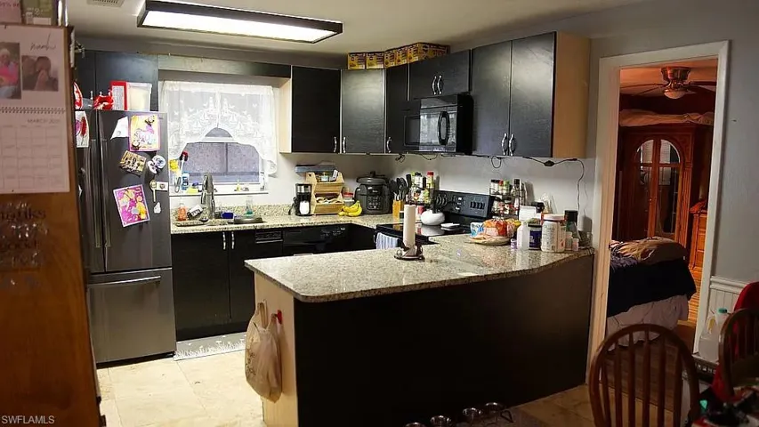 Kitchen featuring black appliances, a peninsula, dark cabinets, and ceiling fan