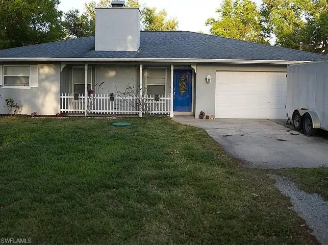 Single story home with a front yard, covered porch, a chimney, driveway, and an attached garage