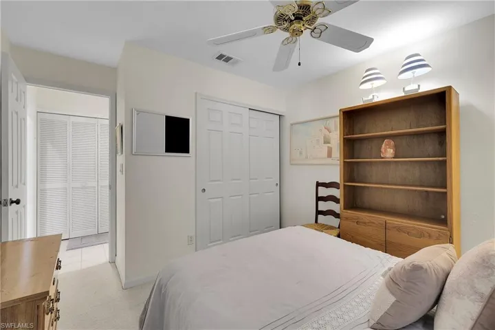 Bedroom with light colored carpet, a ceiling fan, and a closet