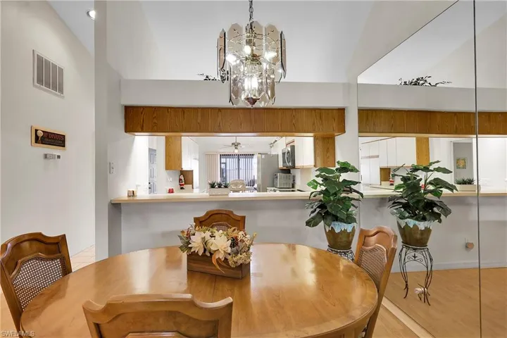 Dining room featuring a ceiling fan, a towering ceiling, light wood-type flooring, and a chandelier