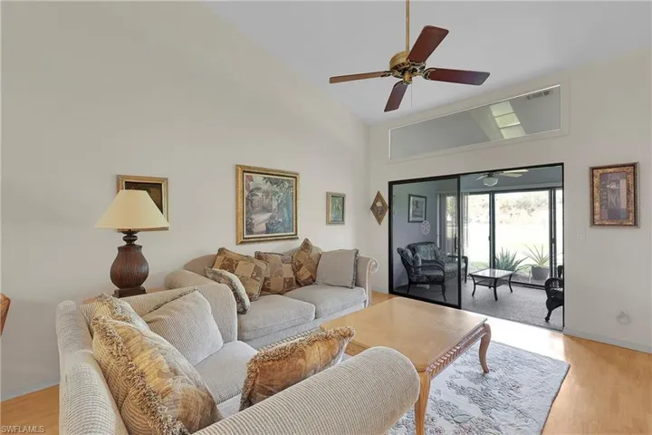 Living area with light wood finished floors, high vaulted ceiling, and a ceiling fan