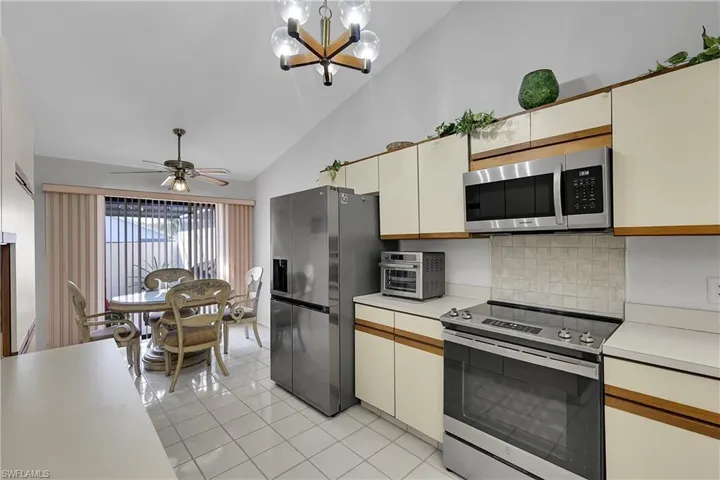 Kitchen with appliances with stainless steel finishes, light countertops, backsplash, a chandelier, and light tile patterned floors