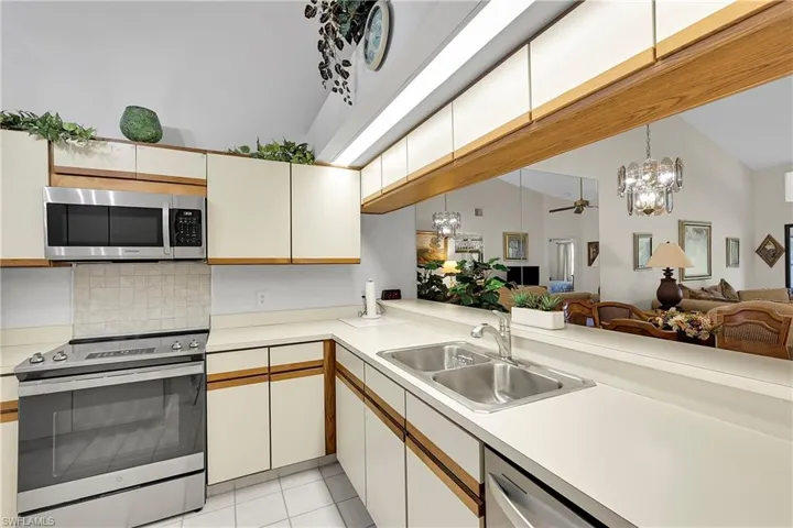 Kitchen with stainless steel appliances, decorative light fixtures, light countertops, open floor plan, and a chandelier