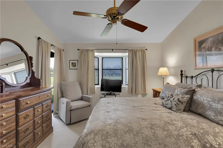 Bedroom with light carpet, a ceiling fan, and vaulted ceiling
