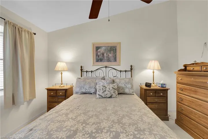 Carpeted master  bedroom with lofted ceiling and ceiling fan