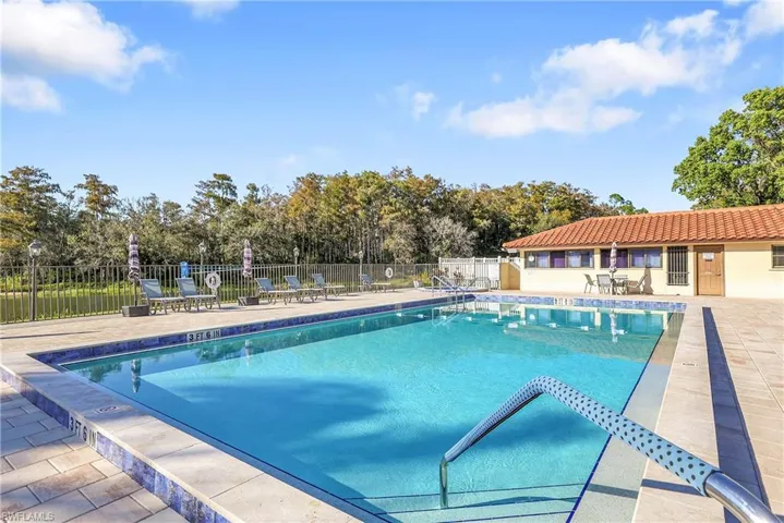 Community pool with a patio area and view of scattered trees