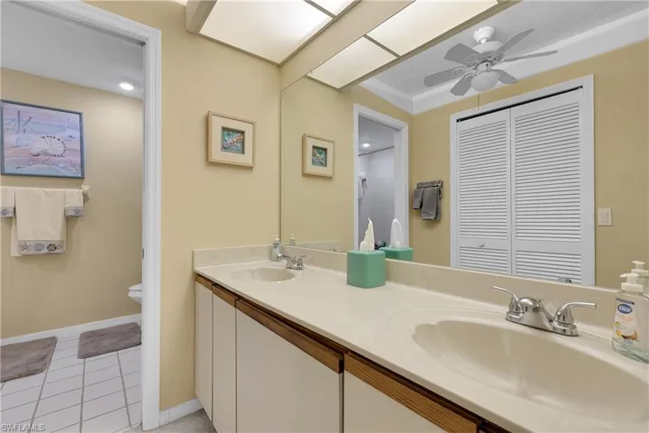 Full bath featuring double vanity, light tile patterned flooring, and a ceiling fan