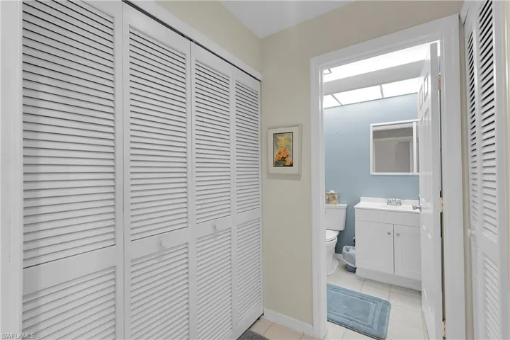 Half bathroom with a closet, vanity, and light tile patterned floors