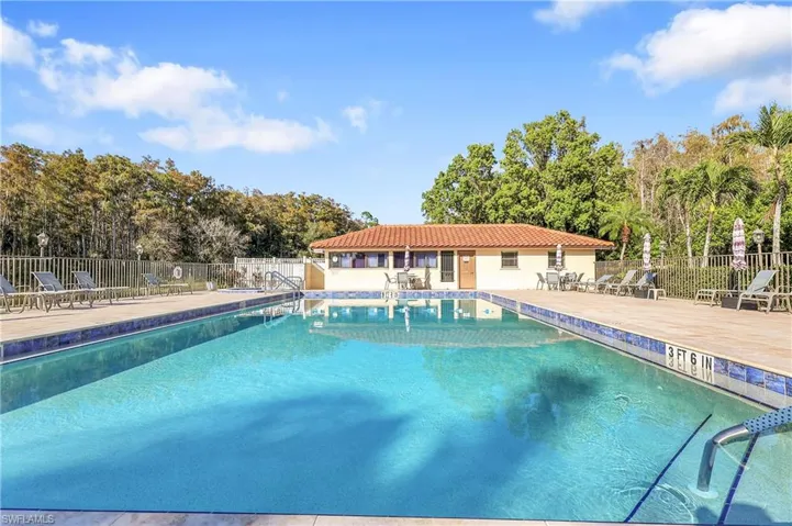 Community pool with a patio and view of wooded area