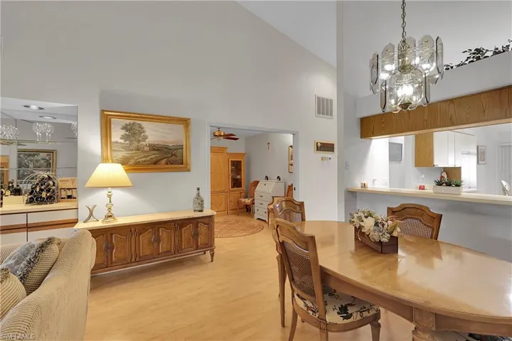 Dining area featuring light wood finished floors, high vaulted ceiling, ceiling fan, and a chandelier