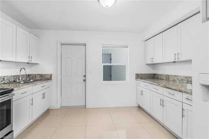 Kitchen featuring white cabinets, light stone countertops, electric stove, and white refrigerator with ice dispenser