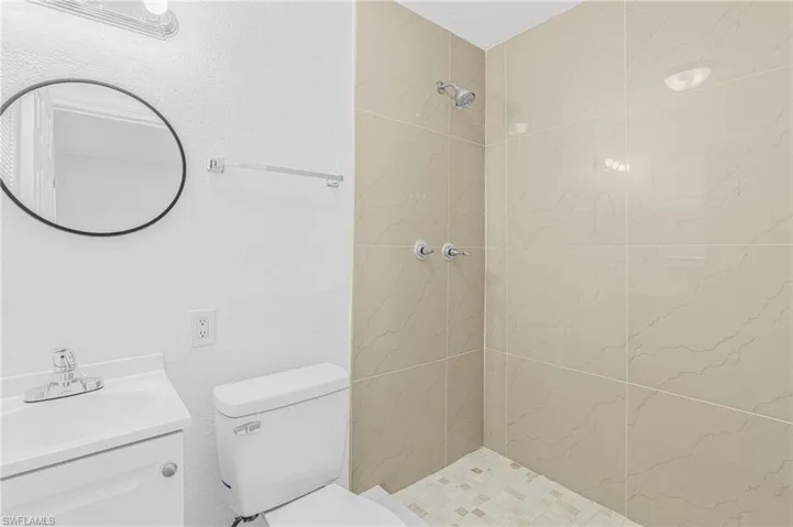 Bathroom with a stall shower, vanity, and a textured wall