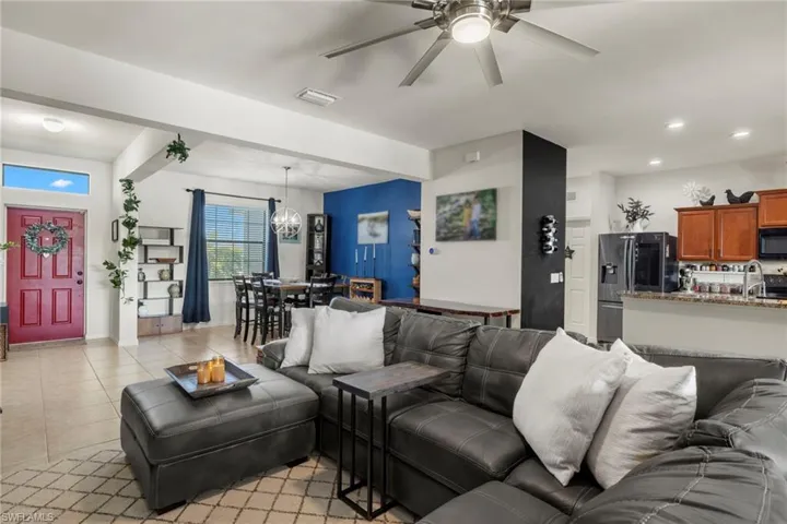 Living room featuring sink, ceiling fan with notable chandelier, and light tile patterned flooring