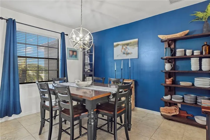 Dining room with light tile patterned flooring and an inviting chandelier