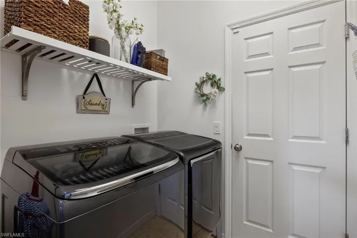 Laundry room with washing machine and dryer and tile patterned floors
