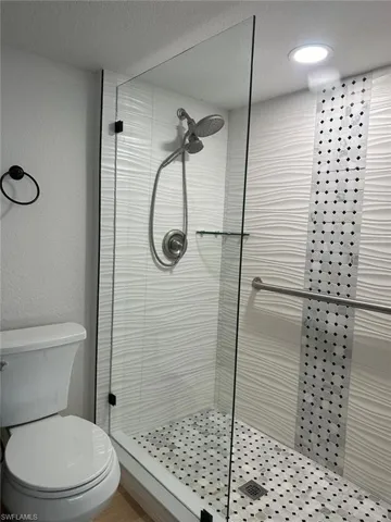 Bathroom with toilet, a textured ceiling, and a shower with door