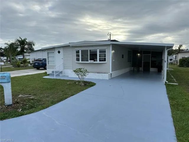 View of front facade featuring a carport and a front lawn