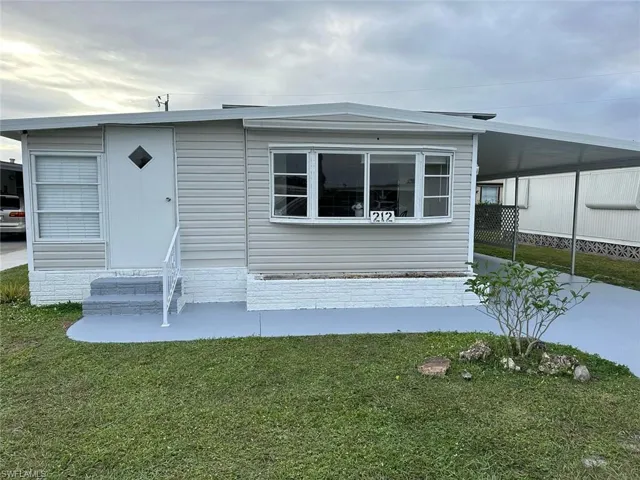 Manufactured / mobile home with a carport and a front yard