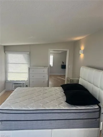 Bedroom with a textured ceiling and a wall mounted air conditioner