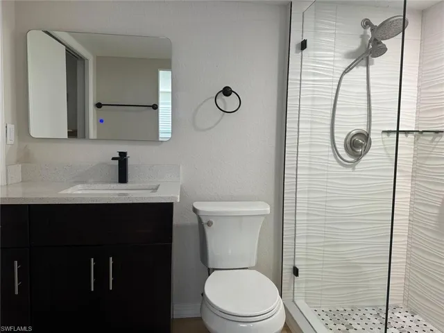Bathroom featuring walk in shower, vanity, and toilet