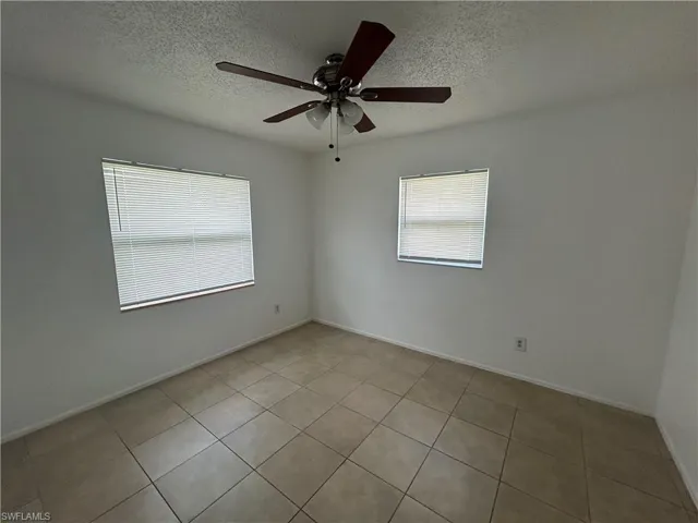 Spare room featuring ceiling fan, a textured ceiling, and light tile patterned flooring