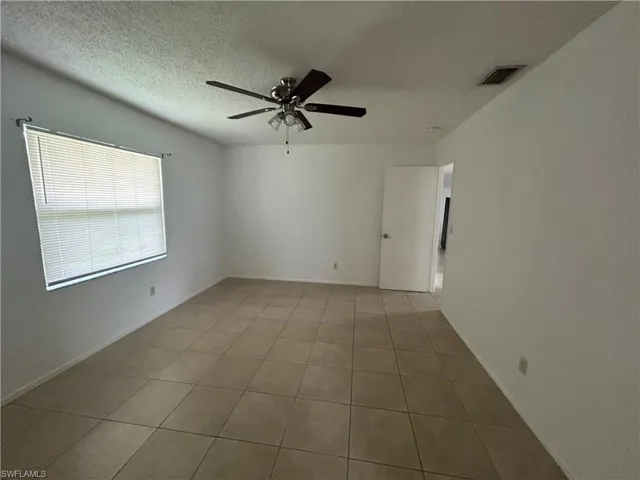 Tiled spare room with a ceiling fan and a textured ceiling