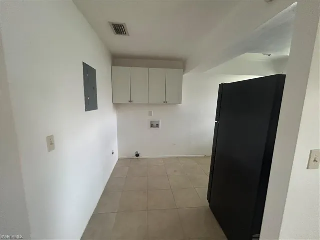 Washroom featuring cabinet space, hookup for a washing machine, light tile patterned floors, electric panel, and hookup for an electric dryer