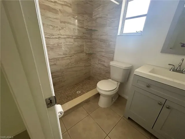 Full bathroom featuring vanity, a tile shower, and tile patterned floors