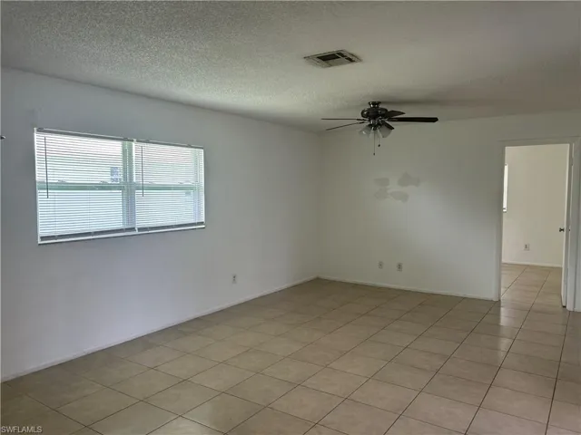 Spare room with ceiling fan, a textured ceiling, and light tile patterned floors