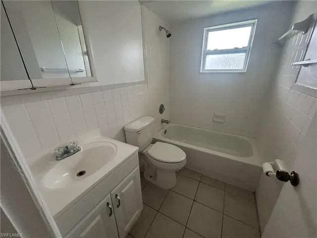 Full bath featuring tile walls,  shower combination, vanity, and tile patterned flooring