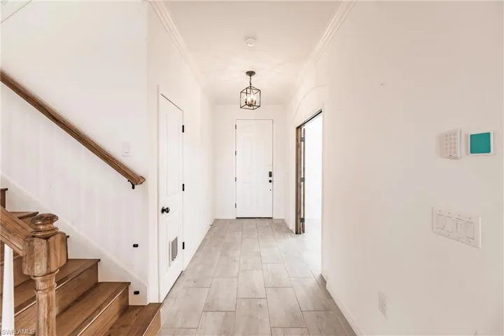 Hall featuring light wood-type flooring, an inviting chandelier, and ornamental molding