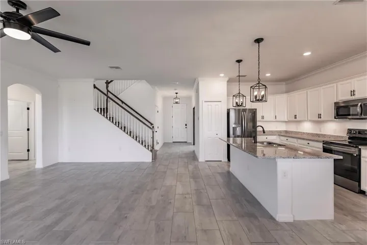 Kitchen with stainless steel appliances, a kitchen island with sink, light hardwood / wood-style floors, and sink