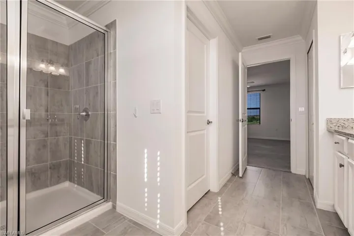 Bathroom with crown molding, vanity, and an enclosed shower