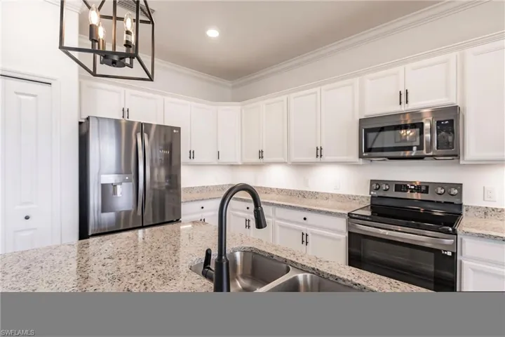 Kitchen with white cabinets, stainless steel appliances, crown molding, and sink