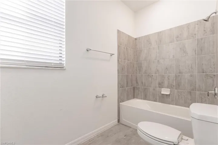 Bathroom featuring tiled shower / bath combo and toilet