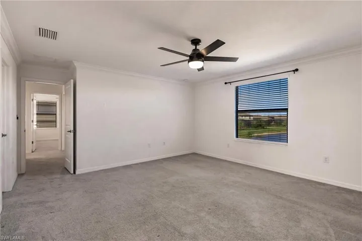 Spare room featuring ceiling fan, light colored carpet, and ornamental molding