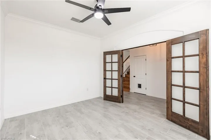 Spare room featuring ceiling fan, french doors, light hardwood / wood-style floors, and ornamental molding