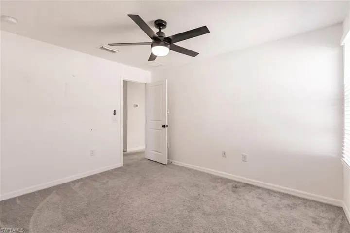 Carpeted empty room with ceiling fan