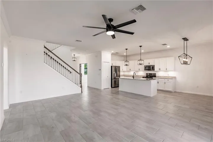 Unfurnished living room featuring light hardwood / wood-style flooring, ceiling fan, crown molding, and sink