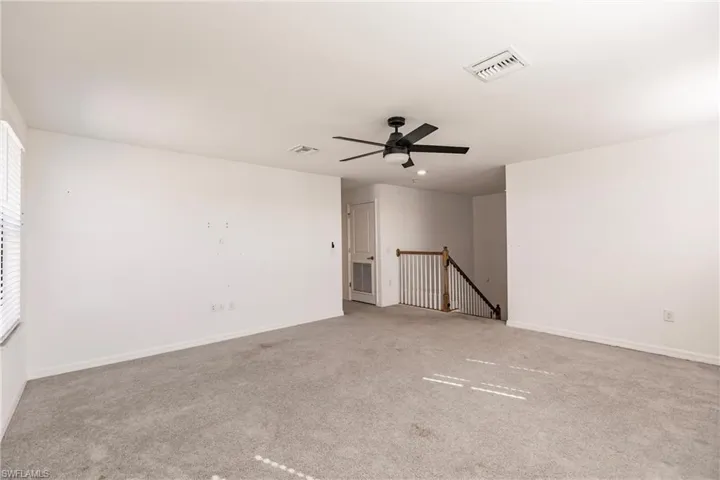 Carpeted spare room featuring ceiling fan