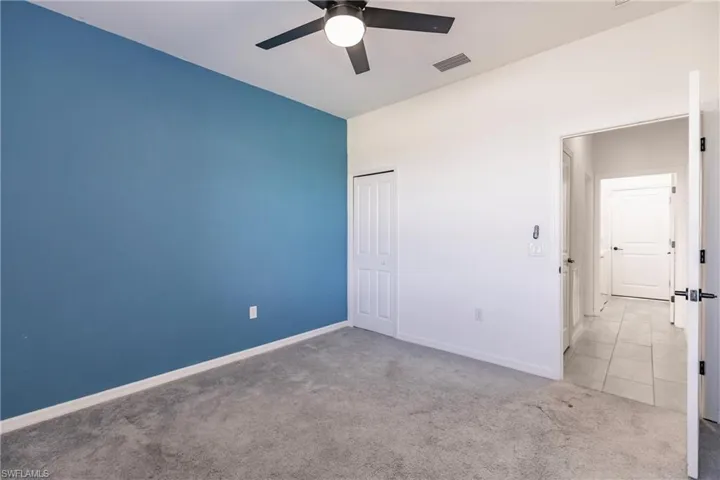 Unfurnished bedroom with ceiling fan, a closet, and light colored carpet