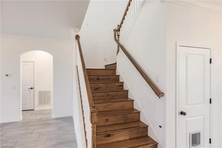 Stairway with crown molding and hardwood / wood-style flooring