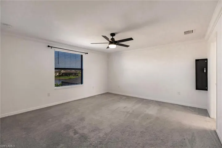Unfurnished room with carpet floors, ceiling fan, and ornamental molding