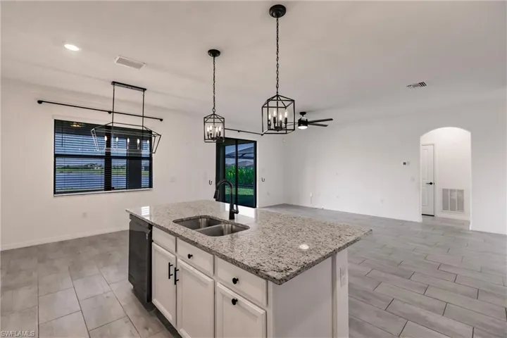 Kitchen featuring white cabinetry, sink, ceiling fan, black dishwasher, and a center island with sink